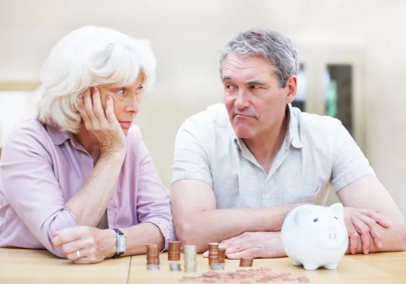 A man and woman sitting at a table with coins.