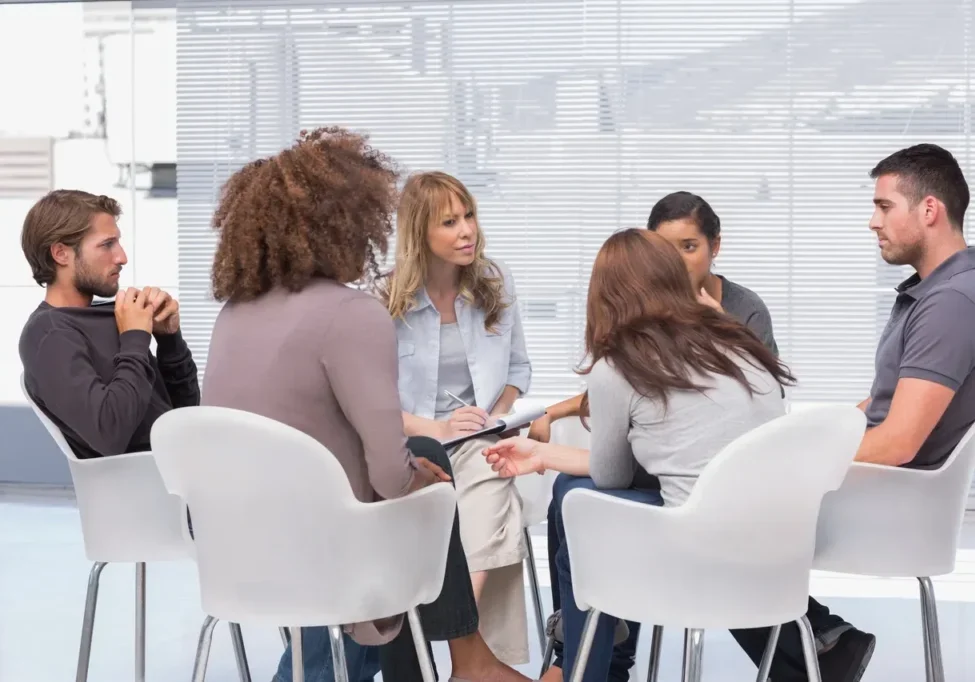 A group of people sitting in chairs around each other.