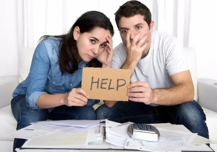 A man and woman sitting in front of a pile of papers.